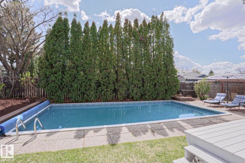 Rectangular swimming pool with a patterned tile border and metal ladder - 1214 85 Street Nw, Edmonton, AB - Outdoor With In Ground Pool