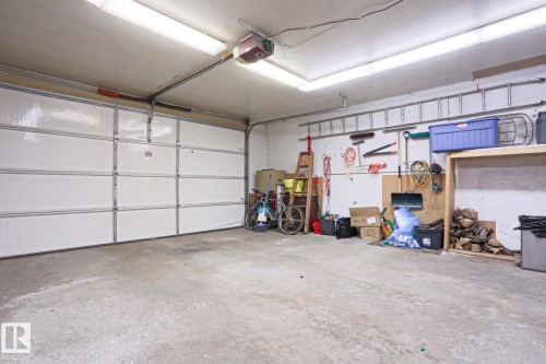 Spacious garage featuring a white panel garage door, concrete flooring, and ceiling-mounted strip lighting - 1214 85 Street Nw, Edmonton, AB - Indoor Photo Showing Garage