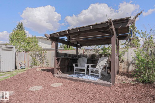 Outdoor wooden pergola with a built-in shelf, elevated deck flooring, and a mulched ground cover - 1214 85 Street Nw, Edmonton, AB - Outdoor With Deck Patio Veranda