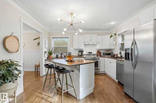 Kitchen featuring a central island with a wood-finish countertop, white cabinetry, stainless steel appliances, and wood-finish flooring - 4 Langley Dr, Fort Saskatchewan, AB - Indoor Photo Showing Kitchen With Upgraded Kitchen