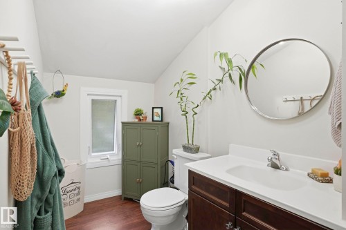Bright bathroom featuring a dark wood-finish vanity with an integrated sink, polished chrome faucet, and a circular wall mirror - 4 Langley Dr, Fort Saskatchewan, AB - Indoor Photo Showing Bathroom