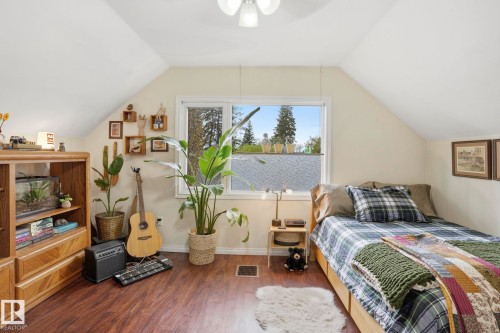 Attic room featuring sloped ceilings, a bright window, wood-finish flooring, and a built-in storage unit - 4 Langley Dr, Fort Saskatchewan, AB - Indoor Photo Showing Bedroom
