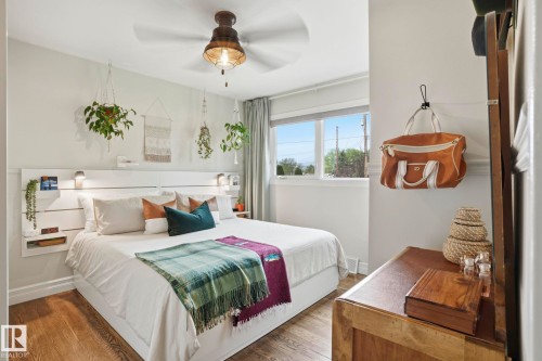 Bedroom featuring wood-finish flooring, a white horizontal plank headboard with integrated shelving and sconce lighting, and a ceiling fan with an industrial-style light fixture - 4 Langley Dr, Fort Saskatchewan, AB - Indoor Photo Showing Bedroom
