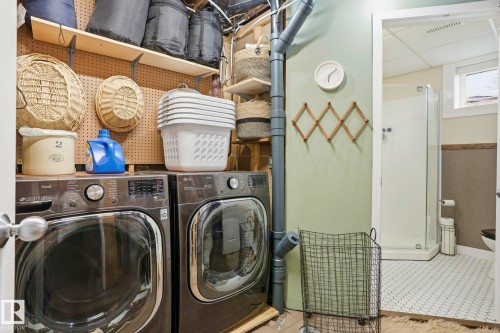 Dedicated laundry area featuring front-loading washer and dryer, adjacent to a bathroom with a shower enclosure - 4 Langley Dr, Fort Saskatchewan, AB - Indoor Photo Showing Laundry Room