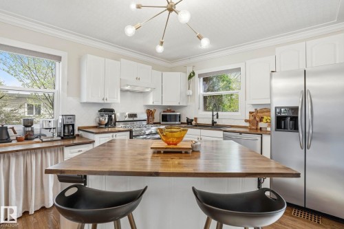 Kitchen featuring a large center island with a wood-finish countertop, white cabinetry, stainless steel appliances, and wood-finish flooring - 4 Langley Dr, Fort Saskatchewan, AB - Indoor Photo Showing Kitchen