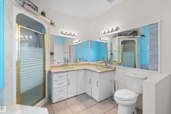 Bathroom featuring a corner vanity with dual vessel sinks, white cabinetry, and a light-toned countertop - 
