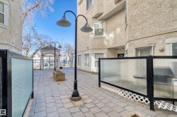 Outdoor paved patio area featuring a paver stone surface, black privacy screens with frosted panels, and exterior wall-mounted lighting - 