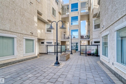 Paver stone courtyard surrounded by multi-story stucco buildings featuring multiple windows and balcony access - 205 10939 82 Avenue, Edmonton, AB - Outdoor
