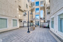 Paver stone courtyard surrounded by multi-story stucco buildings featuring multiple windows and balcony access - 
