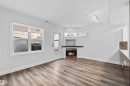 Spacious room featuring wood-finish flooring, a built-in fireplace with a dark mantel, multiple windows, and a glass-paned door - 205 10939 82 Avenue, Edmonton, AB  - Indoor Photo Showing Living Room With Fireplace 