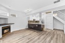 Open-concept living area featuring wood-finish flooring, a built-in fireplace, and a kitchen island with seating - 205 10939 82 Avenue, Edmonton, AB  - Indoor With Fireplace 