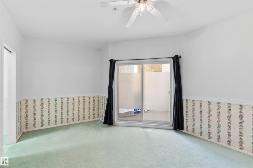Room featuring light green carpeting, a sliding glass door with frosted lower panels, and an overhead ceiling fan with lighting - 205 10939 82 Avenue, Edmonton, AB - Indoor Photo Showing Other Room