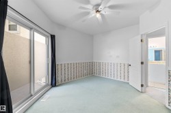 Bright room featuring light blue carpet, a white ceiling fan with integrated lighting, and a sliding glass door providing exterior access - 