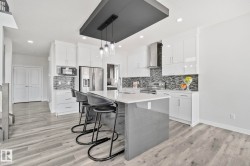 Modern kitchen featuring a central island with a light-toned countertop and seating for three - 
