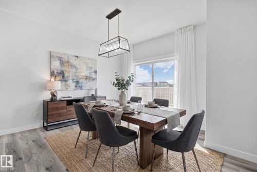 Spacious room featuring light wood-finish flooring, a contemporary linear chandelier, and a large sliding glass door - 334 Aston Close, Leduc, AB - Indoor Photo Showing Dining Room