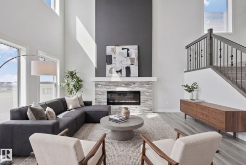 Living area with a two-story ceiling, a fireplace with a stacked stone surround, and a dark accent wall - 334 Aston Close, Leduc, AB - Indoor Photo Showing Living Room With Fireplace