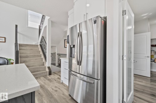 Modern kitchen area featuring a stainless steel refrigerator, white cabinetry, and a light-toned countertop - 334 Aston Close, Leduc, AB - Indoor Photo Showing Kitchen With Upgraded Kitchen