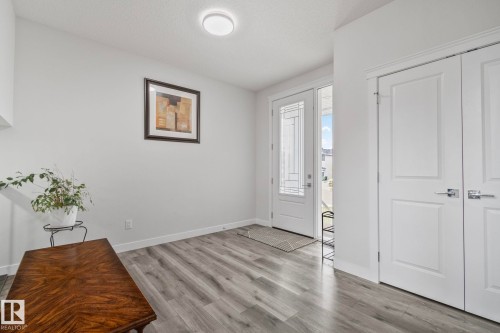 Entryway featuring wood-finish flooring, a white paneled front door with decorative glass, and dual white paneled doors with chrome hardware - 334 Aston Close, Leduc, AB - Indoor Photo Showing Other Room