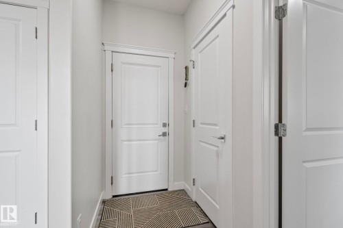 Entryway featuring white paneled doors, chrome hardware, and dark wood-finish flooring - 334 Aston Close, Leduc, AB - Indoor Photo Showing Other Room