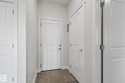 Entryway featuring white paneled doors, chrome hardware, and dark wood-finish flooring - 