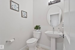 Bright powder room featuring a pedestal sink, oval vanity mirror, and contemporary wall sconce - 