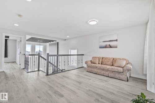 Upper-level landing featuring wood-finish flooring, light gray walls, white trim, and a contemporary ceiling light fixture - 334 Aston Close, Leduc, AB - Indoor