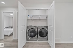 Dedicated laundry closet featuring a stainless steel washer and dryer, upper shelving, and white bi-fold doors - 