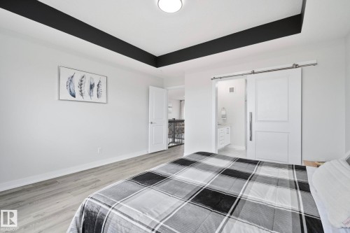 Spacious room featuring a tray ceiling with black accent, wood-finish flooring, and white walls - 334 Aston Close, Leduc, AB - Indoor