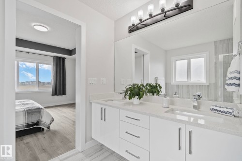Dual-sink vanity featuring a light-toned countertop, integrated rectangular sinks, modern chrome faucets, and a large wall-mounted mirror - 334 Aston Close, Leduc, AB - Indoor Photo Showing Bathroom