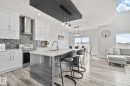 Modern kitchen featuring light cabinetry, stainless steel appliances, a mosaic tile backsplash, and a central island with a sink and seating - 334 Aston Close, Leduc, AB  - Indoor Photo Showing Kitchen With Upgraded Kitchen 