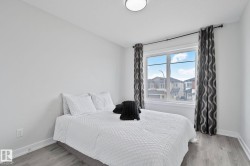Bright room featuring a large window, light-toned walls, wood-finish flooring, and a flush mount ceiling light - 