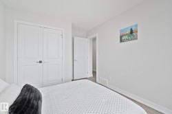 Bedroom featuring light gray walls, white trim, and wood-finish flooring - 