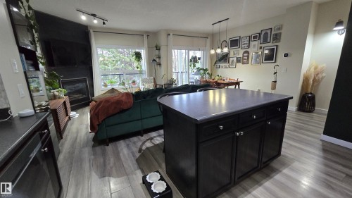 Kitchen island with dark wood-finish cabinetry and a solid surface countertop - 90 3010 33 Avenue, Edmonton, AB - Indoor With Fireplace