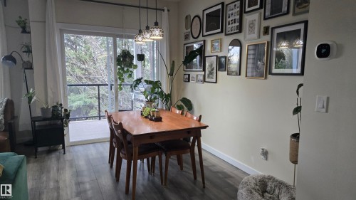 Dining area featuring wood-finish flooring, a gallery wall, and a sliding glass door opening to a private balcony - 90 3010 33 Avenue, Edmonton, AB - Indoor Photo Showing Dining Room