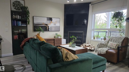 Living area featuring wood-finish flooring and a corner fireplace with a dark surround - 90 3010 33 Avenue, Edmonton, AB - Indoor Photo Showing Living Room With Fireplace