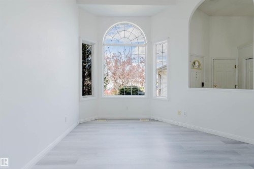 Bay window with arched transom, light wood-finish flooring, white baseboards, and an arched wall opening - 13755 131B Avenue, Edmonton, AB - Indoor Photo Showing Other Room