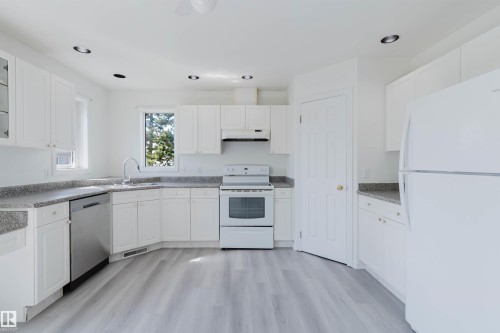 Kitchen featuring abundant white cabinetry, light-toned countertops, wood-finish flooring, a stainless steel dishwasher, and recessed ceiling lights - 13755 131B Avenue, Edmonton, AB - Indoor Photo Showing Kitchen