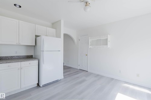 Kitchenette featuring a white refrigerator and white cabinetry with speckled countertops - 13755 131B Avenue, Edmonton, AB - Indoor Photo Showing Kitchen