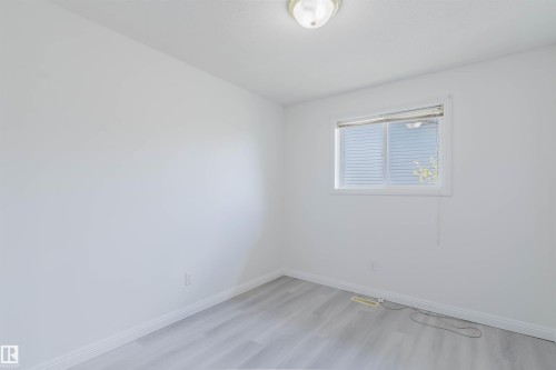 Bright interior space featuring light wood-finish flooring, white walls, and a window with blinds - 13755 131B Avenue, Edmonton, AB - Indoor Photo Showing Other Room
