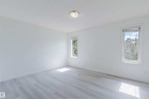 Spacious room featuring light wood-finish flooring, bright white walls, and two windows with white trim - 13755 131B Avenue, Edmonton, AB - Indoor Photo Showing Other Room