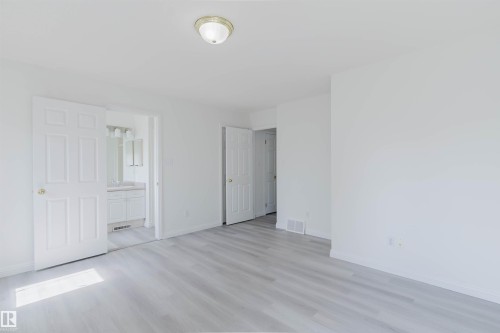 Spacious interior featuring light wood-finish flooring, white walls, and a ceiling-mounted light fixture - 13755 131B Avenue, Edmonton, AB - Indoor Photo Showing Other Room