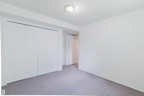 Bedroom featuring light gray carpeting, white walls, and a white bi-fold closet door system - 13755 131B Avenue, Edmonton, AB - Indoor Photo Showing Other Room