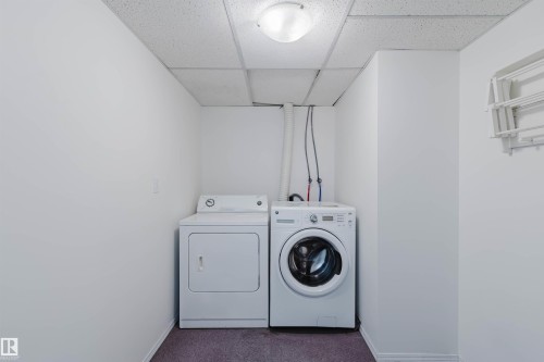 Dedicated laundry area featuring a front-load washing machine, a white dryer, and a neutral wall-mounted drying rack - 13755 131B Avenue, Edmonton, AB - Indoor Photo Showing Laundry Room