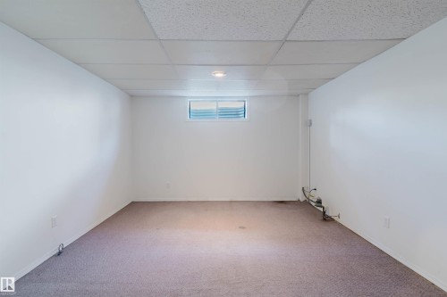 Spacious room featuring neutral carpet flooring, white painted walls, and a drop ceiling with recessed lighting - 13755 131B Avenue, Edmonton, AB - Indoor