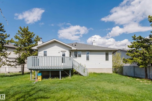 Spacious backyard featuring a light gray wood deck with coordinating railings and stairs, a manicured lawn, and mature evergreen trees - 13755 131B Avenue, Edmonton, AB - Outdoor