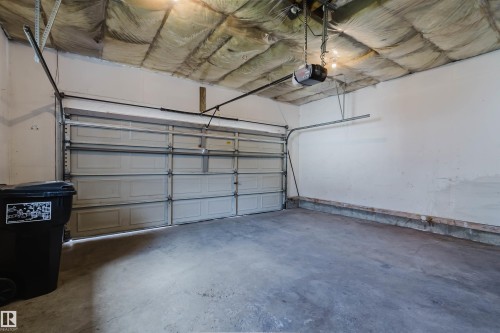 Garage interior featuring a concrete floor, white painted walls, and an automatic garage door opener - 13755 131B Avenue, Edmonton, AB - Indoor Photo Showing Garage
