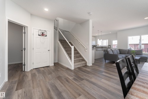 Main level featuring wood-finish flooring, a carpeted staircase with metal balusters, and recessed lighting - 5323 Lark Landing Landing, Edmonton, AB - Indoor