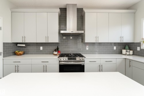 Modern kitchen featuring light gray cabinetry, a stainless steel range hood, a gas range with five burners, and a subway tile backsplash - 5323 Lark Landing Landing, Edmonton, AB - Indoor Photo Showing Kitchen With Upgraded Kitchen