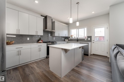 Modern kitchen featuring light gray cabinetry, quartz countertops, a subway tile backsplash, stainless steel appliances, and wood-finish flooring - 5323 Lark Landing Landing, Edmonton, AB - Indoor Photo Showing Kitchen With Upgraded Kitchen