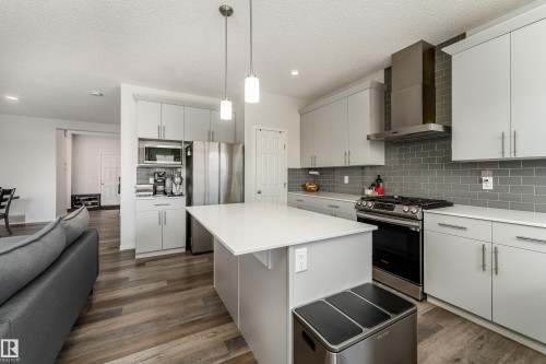Contemporary kitchen featuring light gray cabinetry, stainless steel appliances, a subway tile backsplash, and wood-finish flooring - 5323 Lark Landing Landing, Edmonton, AB - Indoor Photo Showing Kitchen With Upgraded Kitchen